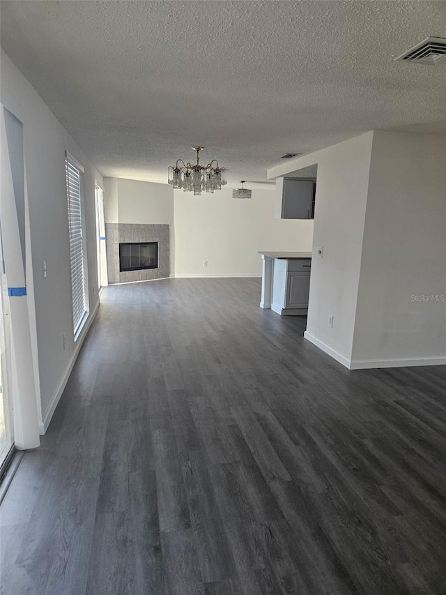 6241 Westport Dr, Port Richey, FL 34668 - unfurnished living room with dark wood-type flooring, visible vents, a textured ceiling, and a notable chandelier