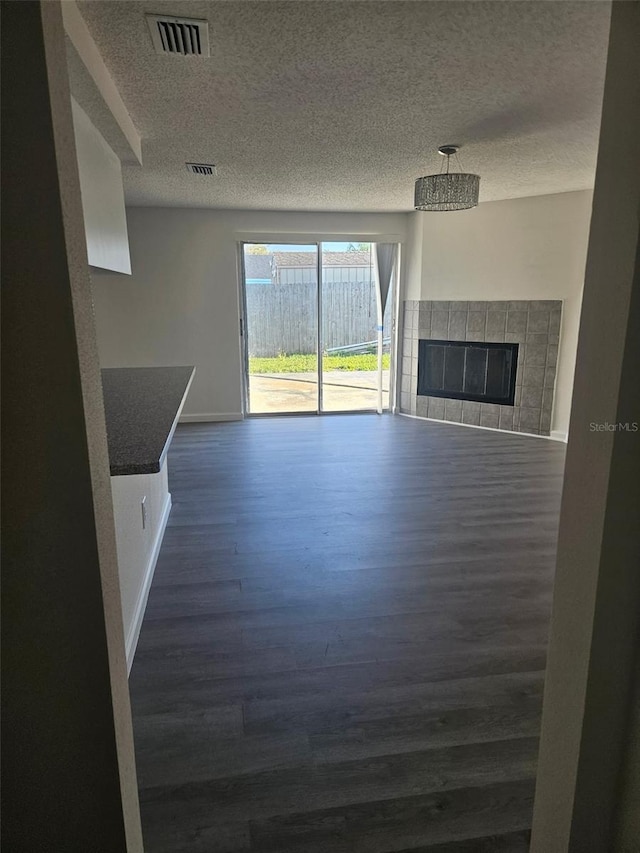6241 Westport Dr, Port Richey, FL 34668 - unfurnished living room featuring dark wood finished floors, a textured ceiling, visible vents, and a fireplace
