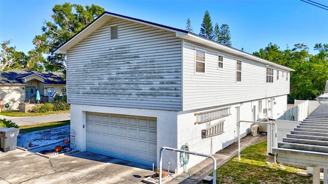 view of side of property with concrete driveway and an attached garage