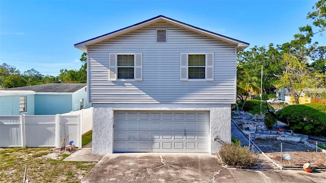 view of home's exterior featuring a garage, stucco siding, concrete driveway, and fence