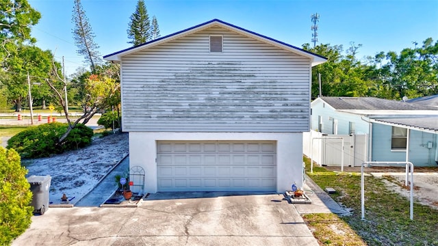 view of side of property featuring stucco siding, fence, and concrete driveway