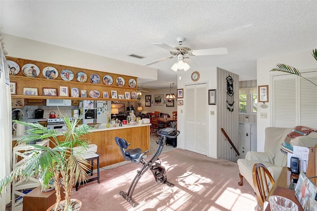 interior space featuring a textured ceiling, visible vents, a ceiling fan, and light colored carpet