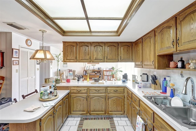 kitchen featuring a sink, light tile patterned flooring, light countertops, a peninsula, and visible vents