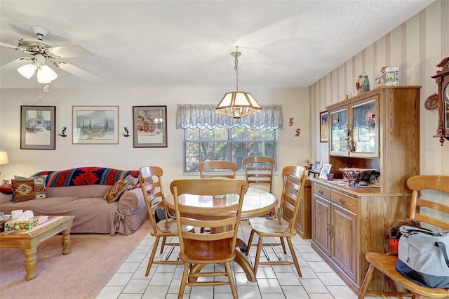 dining space with ceiling fan with notable chandelier, a textured ceiling, and light tile patterned floors