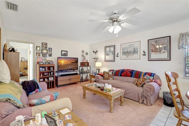 living area with a textured ceiling, visible vents, light colored carpet, and ceiling fan
