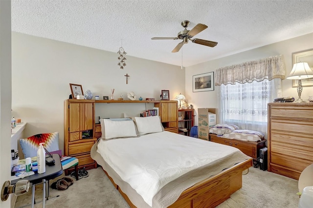 bedroom with light colored carpet, a ceiling fan, and a textured ceiling