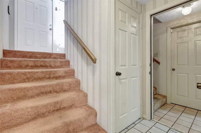 staircase with wallpapered walls and tile patterned flooring