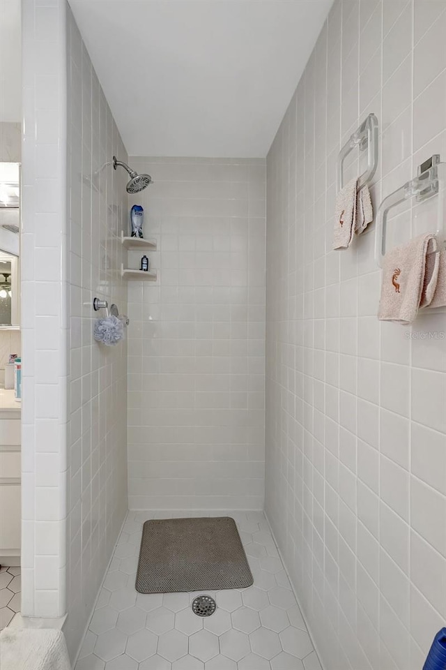 bathroom featuring tile walls, vanity, tile patterned flooring, and a tile shower