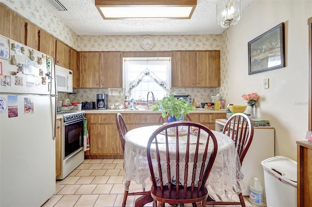 kitchen featuring brown cabinets, visible vents, white appliances, and light countertops