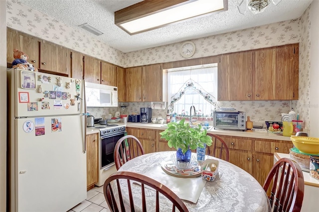 kitchen with light countertops, wallpapered walls, a toaster, and white appliances