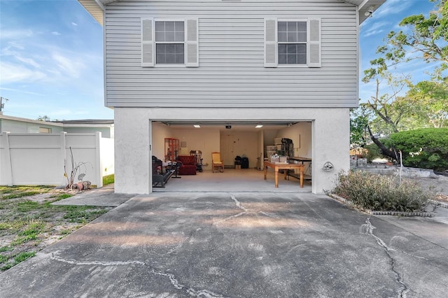 back of property with stucco siding, an attached garage, driveway, and fence