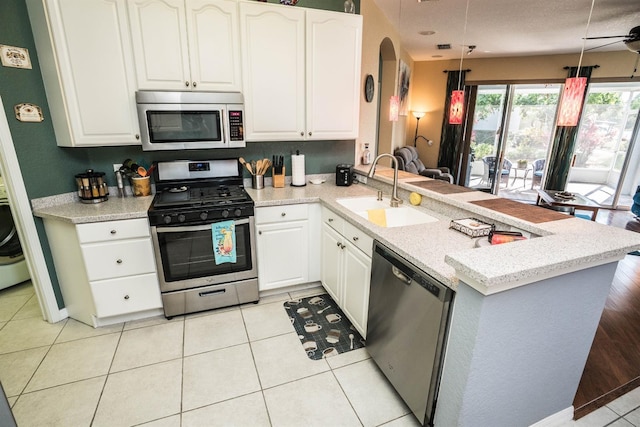 kitchen with a sink, arched walkways, stainless steel appliances, a peninsula, and white cabinetry