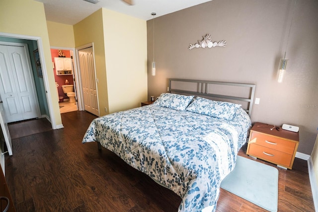 bedroom with visible vents, baseboards, wood finished floors, and connected bathroom