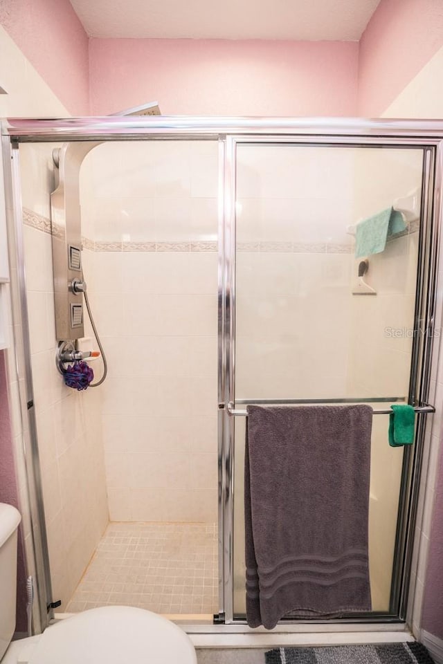 full bathroom featuring a stall shower and toilet