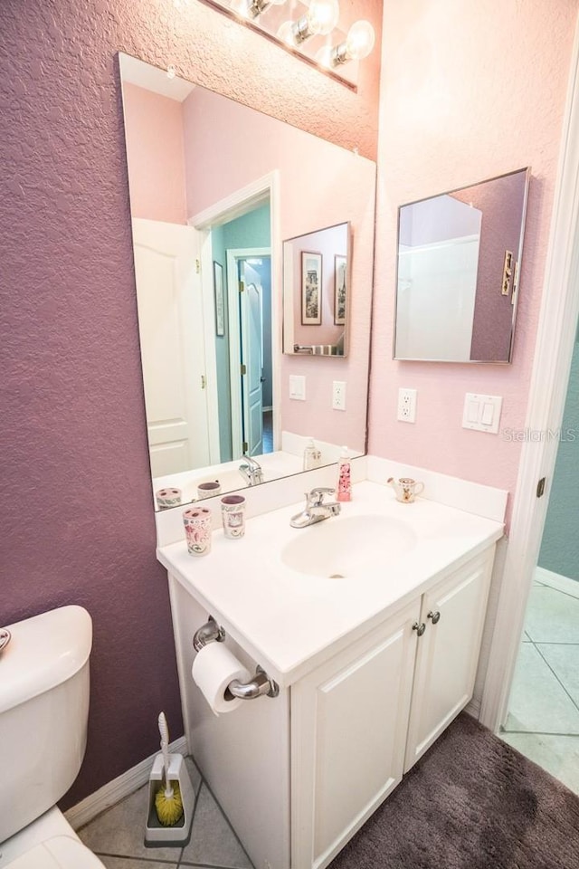 bathroom with toilet, a textured wall, vanity, and tile patterned floors