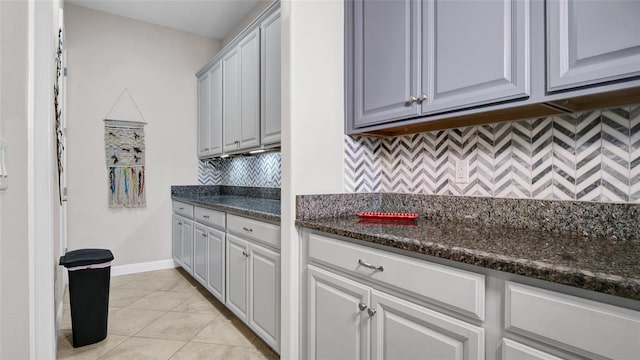 11720 Navajo Sandstone St, Riverview, FL 33579 - kitchen with light tile patterned floors, baseboards, decorative backsplash, and dark stone countertops