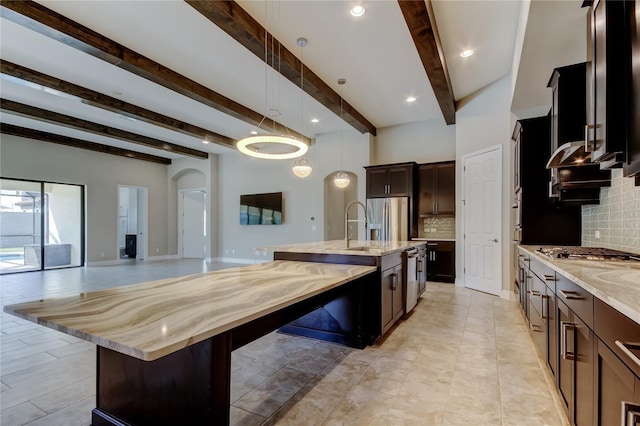 4975 Night Star Trl, Odessa, FL 33556 - kitchen featuring arched walkways, beam ceiling, open floor plan, tasteful backsplash, and light stone countertops