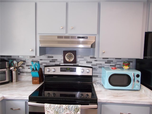 kitchen featuring light stone counters, decorative backsplash, under cabinet range hood, and stainless steel electric range oven