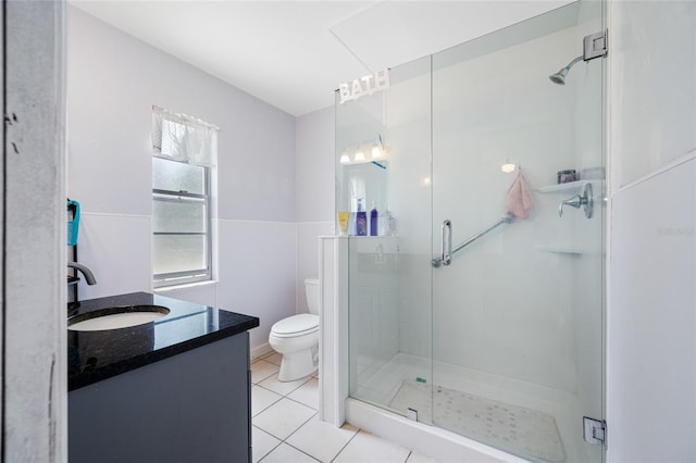 bathroom with tile patterned flooring, vanity, toilet, and a stall shower
