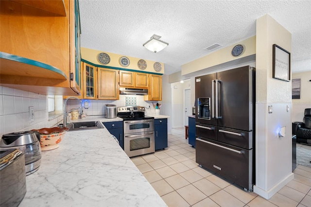 kitchen with a sink, high quality fridge, light countertops, range with two ovens, and under cabinet range hood