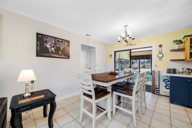 dining area with light tile patterned floors, a chandelier, visible vents, and a textured ceiling