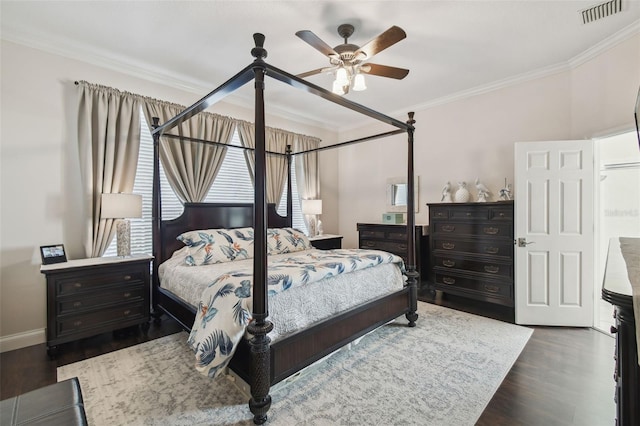 bedroom featuring a ceiling fan, visible vents, crown molding, wood finished floors, and baseboards