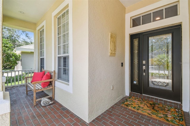 entrance to property with covered porch and stucco siding