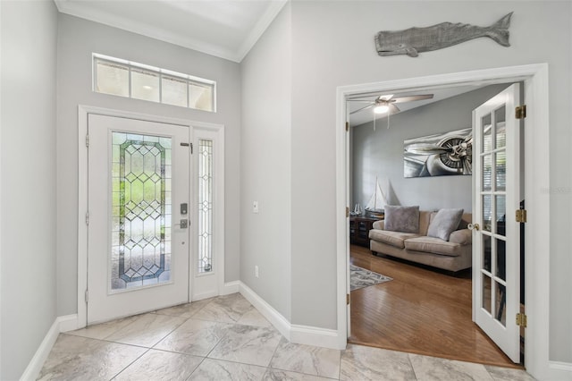 foyer with baseboards, ornamental molding, a ceiling fan, and french doors