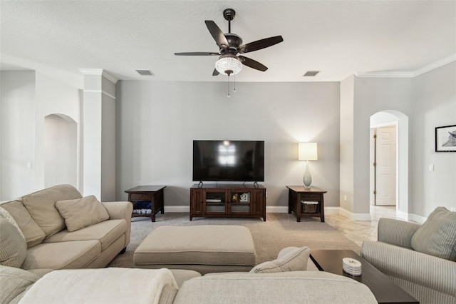 living room with crown molding, arched walkways, baseboards, and a ceiling fan