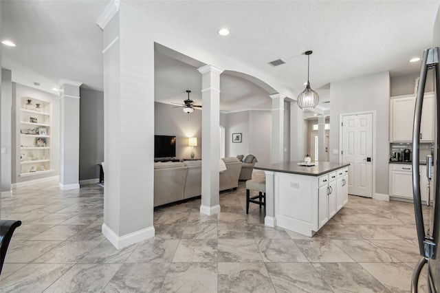 kitchen featuring a ceiling fan, dark countertops, built in shelves, marble finish floor, and ornate columns