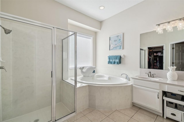 bathroom featuring a walk in closet, tile patterned flooring, vanity, a garden tub, and a stall shower