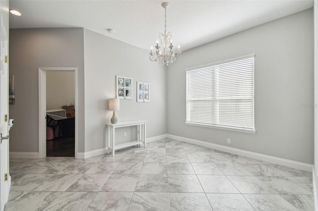 empty room with an inviting chandelier, marble finish floor, and baseboards