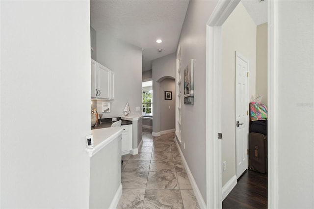 corridor with arched walkways, baseboards, recessed lighting, and marble finish floor