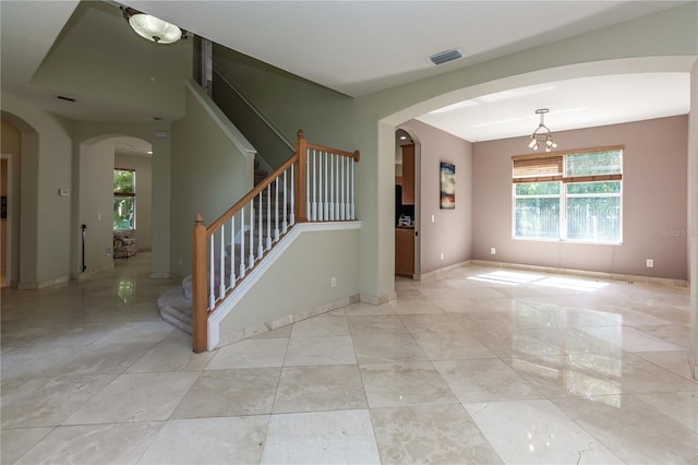 11102 Avery Oaks Dr, Tampa, FL 33625 - unfurnished room featuring stairway, visible vents, arched walkways, baseboards, and a chandelier
