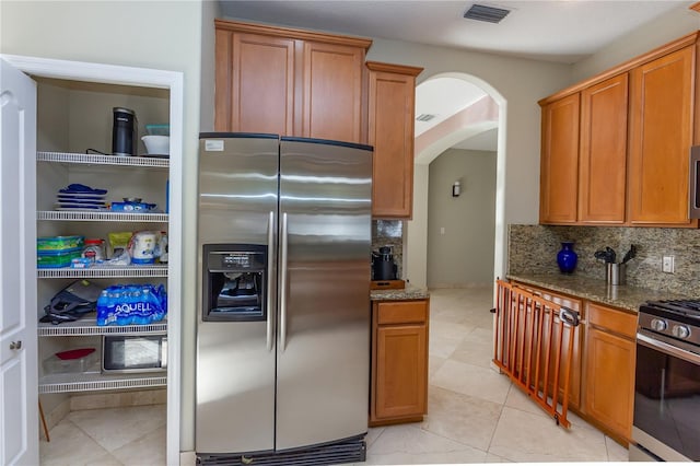 11102 Avery Oaks Dr, Tampa, FL 33625 - kitchen featuring visible vents, arched walkways, dark stone counters, tasteful backsplash, and appliances with stainless steel finishes