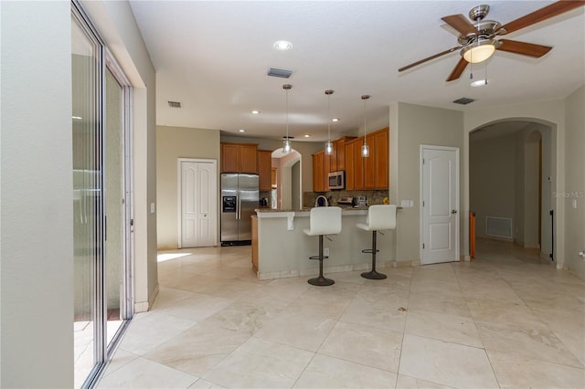 11102 Avery Oaks Dr, Tampa, FL 33625 - kitchen featuring a kitchen breakfast bar, brown cabinets, arched walkways, a peninsula, and appliances with stainless steel finishes