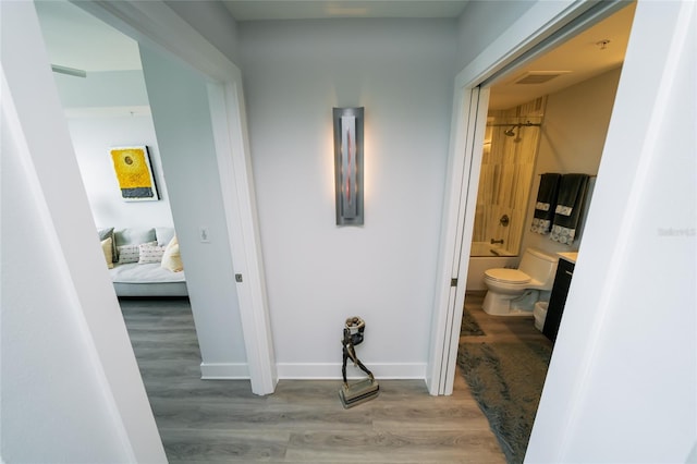 corridor with baseboards, visible vents, and wood finished floors