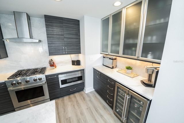 kitchen featuring high end stove, wall chimney exhaust hood, decorative backsplash, light wood-type flooring, and recessed lighting