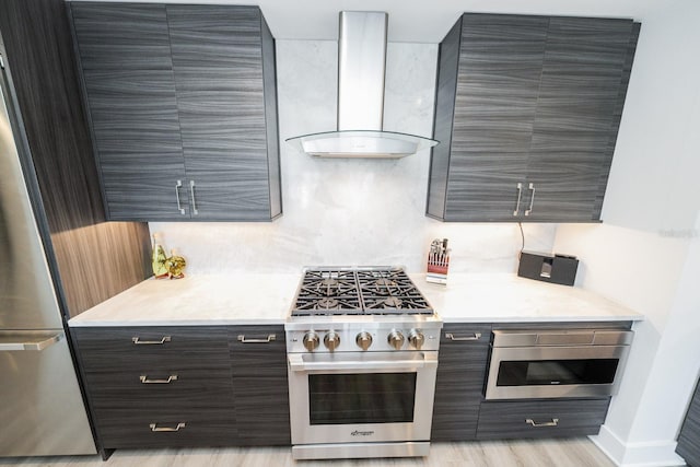 kitchen with wall chimney range hood, light countertops, stainless steel appliances, and modern cabinets