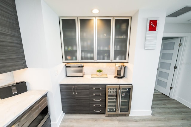 bar with visible vents, light wood-style flooring, baseboards, and wine cooler
