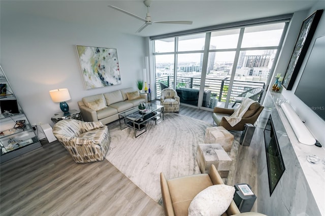 living area with floor to ceiling windows, ceiling fan, and wood finished floors