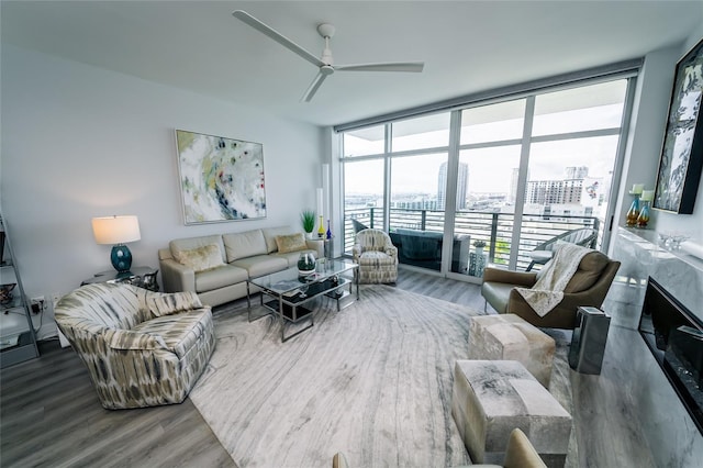 living room with a wall of windows, wood finished floors, and ceiling fan