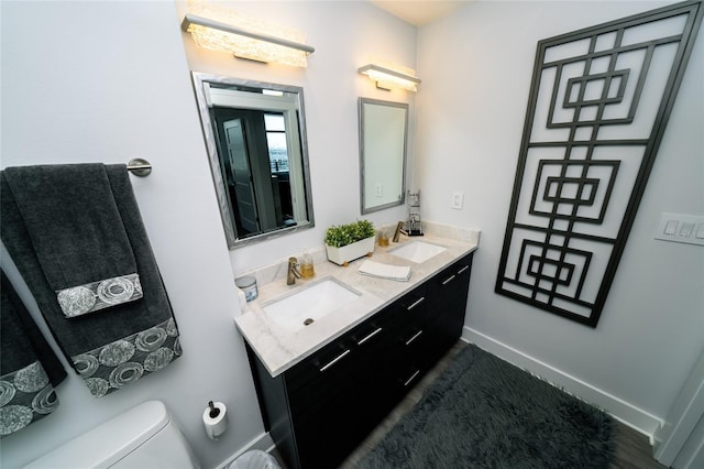 full bathroom featuring toilet, double vanity, and baseboards