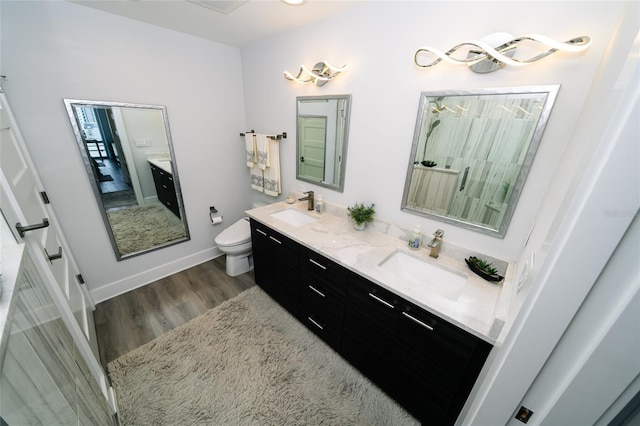 bathroom featuring double vanity, toilet, wood finished floors, and a sink