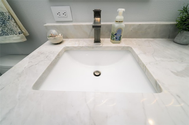 bathroom view of vanity, a textured wall, and toilet