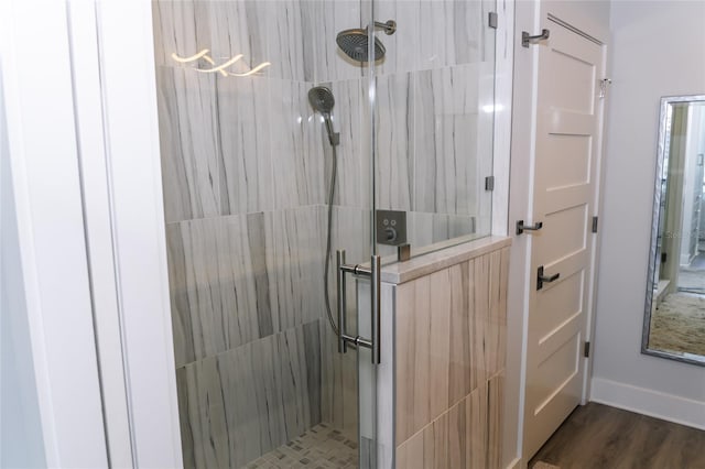 full bathroom with baseboards, wood finished floors, and a stall shower