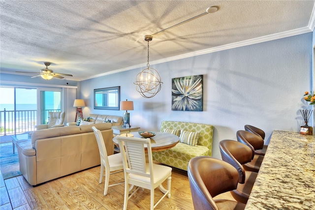 7480 Bayshore Dr Unit 402, Treasure Island, FL 33706 - dining space featuring a textured ceiling, ornamental molding, light wood finished floors, a ceiling fan, and a chandelier
