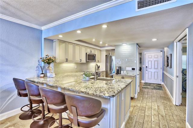 7480 Bayshore Dr Unit 402, Treasure Island, FL 33706 - kitchen with appliances with stainless steel finishes, a textured ceiling, cream cabinets, light wood-type flooring, and backsplash