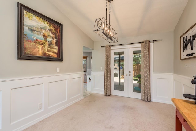 interior space featuring carpet, a decorative wall, wainscoting, and french doors