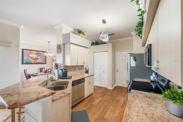 708 Sandy Hills Ave, Tarpon Springs, FL 34689 - kitchen with stainless steel appliances, a peninsula, light wood finished floors, ornamental molding, and a kitchen bar